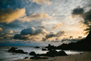 Gökyüzünde altın bulutlar, okyanus üzerinde sarı ve mavi ışık