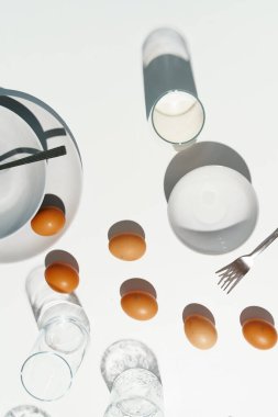 Beyaz masanın üzerinde yumurta ve süt var.