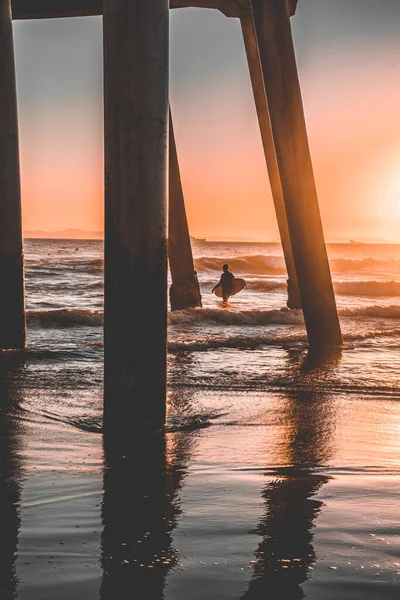 桟橋の下に夕日の波をキャッチサーファー — ストック写真