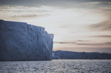 Gün batımında denizde yüzen büyük buzdağları