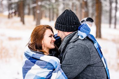Couple Wrapped in a Blue Blanket in a Snowy Pine Forest clipart