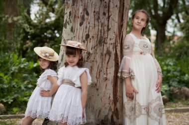 Komünyon kızı parkta ikiz kız kardeşleriyle poz veriyor.