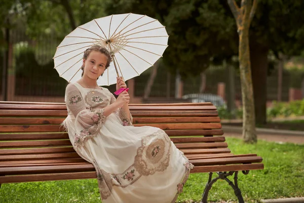 在公园的长椅上摆着一把白色雨伞 摆出通婚女孩的姿势 — 图库照片