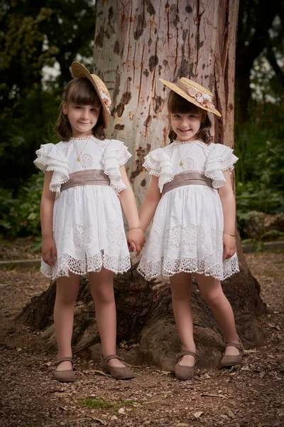 Komünyon ikizleri parkta büyük bir ağacın yanında.