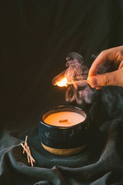 Yanan kibrit ve yanan ahşap fitil mumu ile el.