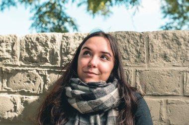 Genç ve güzel bir kadın gülümsüyor ve bir fikri varmış gibi yukarı bakıyor.