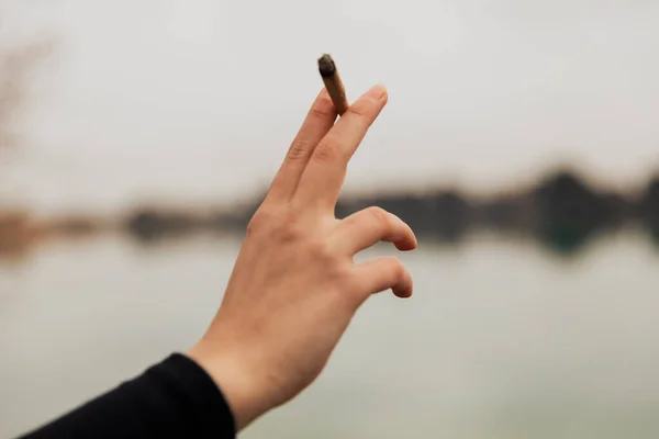 Mão Uma Jovem Segurando Cigarro Maconha Lago Livre — Fotografia de Stock