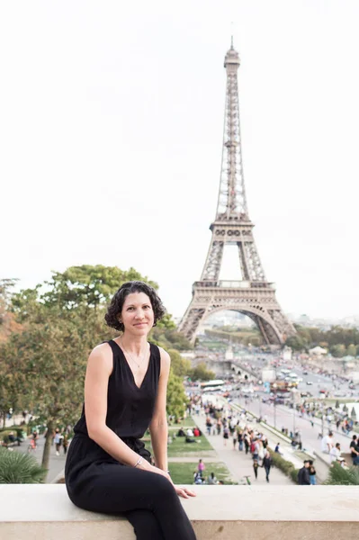 身穿黑色连衣裙的女游客在埃菲尔铁塔前微笑 — 图库照片