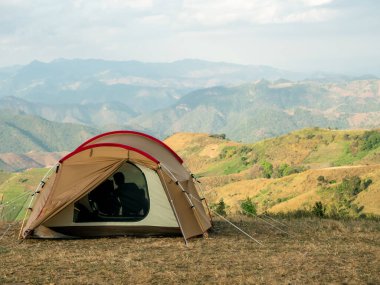 Mountain view in the evening with a tent in Thailand. Camping with a beautiful scenic view of the mountain range in Chiang Mai, Thailand. One tent with The shadow of the person sitting on the chair in front of the tent.