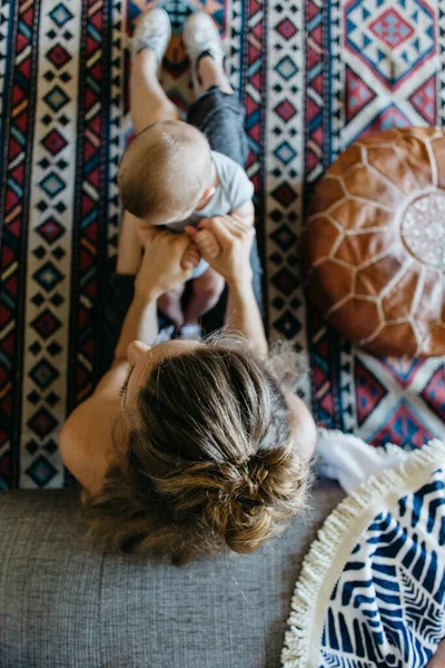 Anne, bebekle yerde oturmuş oynuyor.