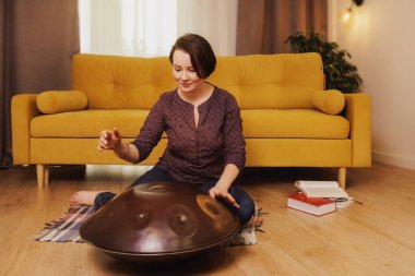 Kadın evde müzik aleti çalıyor.