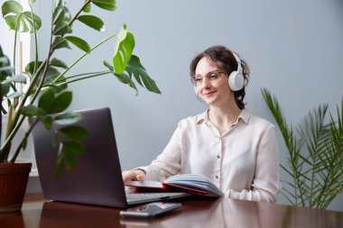 Orta yaşlı biri internetteki bir web sitesinde dizüstü bilgisayar ve kulaklık kullanarak yer alıyor. Müşterilerle video görüşmesi ya da uzaktan bir arkadaşla kişisel sohbet.