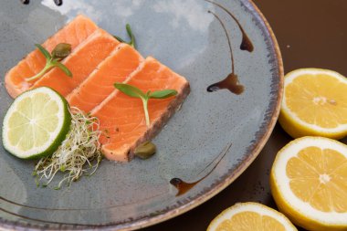 Limon dilimleri ve mikro yeşilliklerle dilimlenmiş kırmızı balık.