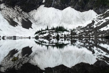 22 Gölü 'nün durgun sularına küçük bir tepe yansıdı. Washington Cascades' e kurulmuş küçük bir göl..