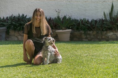 Yazın çimlerin üzerinde köpeğiyle poz veren genç Latin kız.