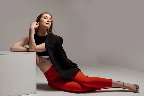 Kvinna Modell Klädd Röda Byxor Och Svart Jacka Poserar Studio — Stockfoto