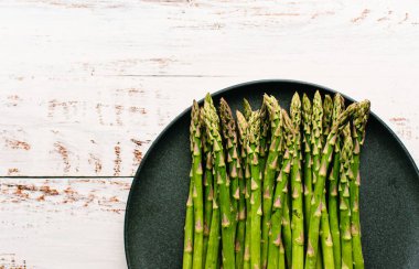 Kırsal beyaz masa üzerinde kaplanmış taze kuşkonmaz mızrakları..
