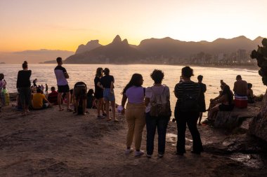 Ipanema Sahili, Rio de Janeiro, Brezilya 'daki kayalıklardan gün batımının keyfini çıkaran insanlara güzel bir manzara