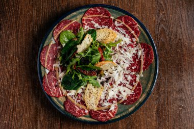 Soslu ve otlu bir tabakta mermer sığır carpaccio.