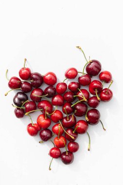 Beyaz bir ağaçta kalp şeklinde kırmızı kirazlar.