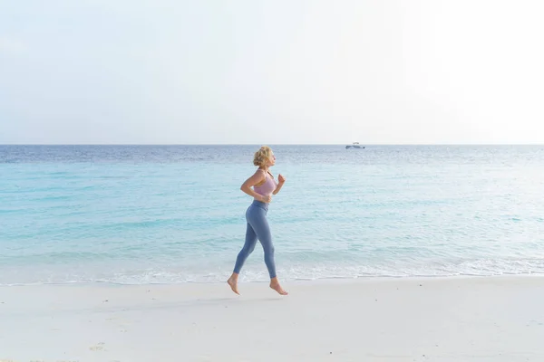 在海滩上慢跑的女运动员 — 图库照片