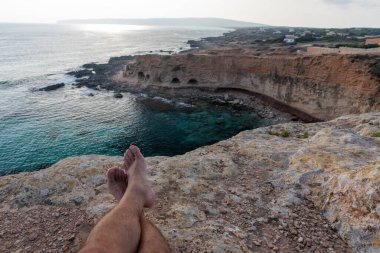 Akdeniz sahilinde bacak bacak üstüne atmış bir adam. Mate, Paraguay, Arjantin, Brezilya ve Uruguay 'dan tipik bir içecek..