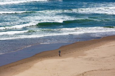 Sahilde tek başına yürüyen bir yolcu.