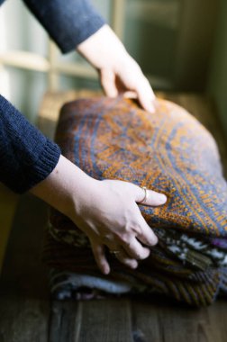Elle örgü ören bir kadının elleri şifoniyerin üzerinde.