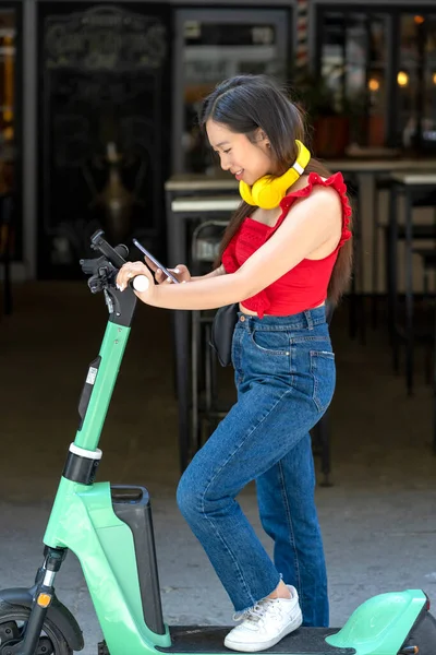 Aziatische Meisje Huren Van Een Scooter Met Haar Smartphone — Stockfoto