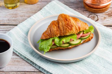 Sosisli kruvasan, salatalık ve hindi kahveli marul yaprağı. 