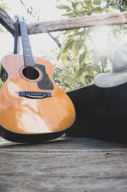 Tahtadaki gitar artı bir saksafon çantası ve şapka.