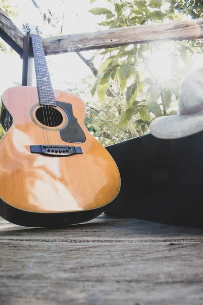 guitar on wood plus a saxophone case and hat