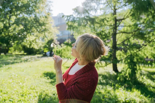一个女人在阳光灿烂的夏日吹蒲公英 — 图库照片