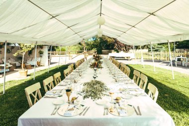 Mumlar, çiçekler ve masa koşucusuyla dolu uzun bir masa. Düğün masası.