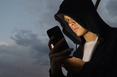 Alacakaranlıkta cep telefonu kullanan bir adam.