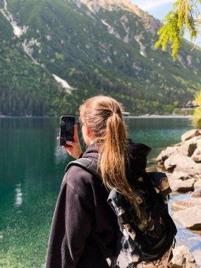 Genç bir kadın Tatras 'taki Morskie Gölü' nün fotoğraflarını çekiyor.