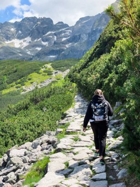 Sırt çantalı genç bir turist dağ yolunda yürüyor.