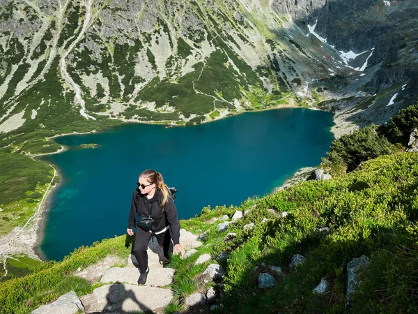 woman tourist with backpack walking in mountains with lake view