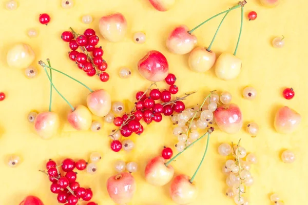 Yellow and red currants with yellow cherries on a yellow background