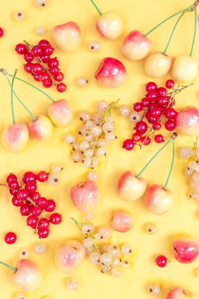 Yellow and red currants with yellow cherries on a yellow background