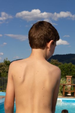 Çocuk güneşli bir günde havuzda oynuyor.