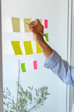 Yaratıcı kadın ev ofisinde yapışkan notlar yazıyor.