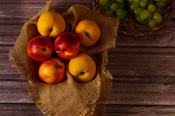 group of fresh nectarines on a raffia cloth with a dark wood background