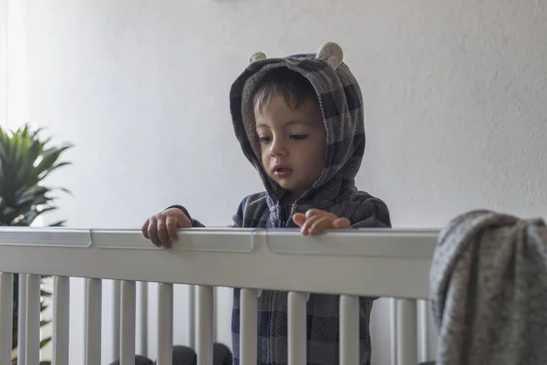 Cute Latin Baby Boy Standing His Crib Wearing Hood — Stock Fotó