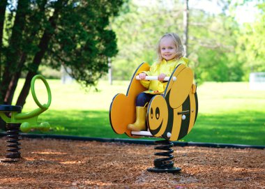 Little blond girl playing at the park on bee ride.