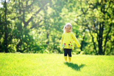 Blond toddler girl in yellow raincoat.