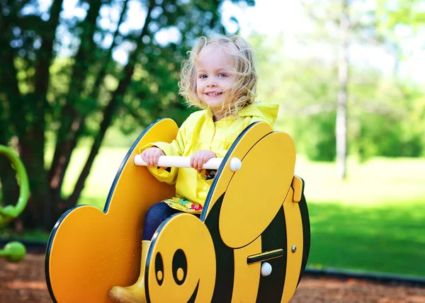 Blond Toddler Girl Yellow Raincoat Bee Ride Playground — Fotografia de Stock