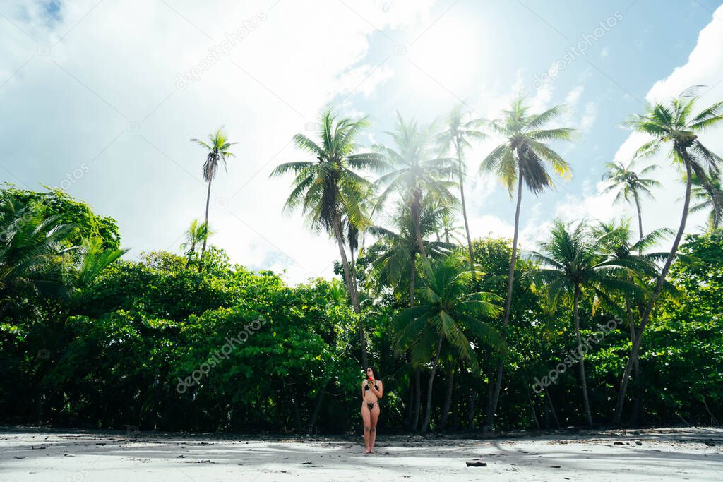 woman with a coconut on the beach of Manuel Antonio with the jungle