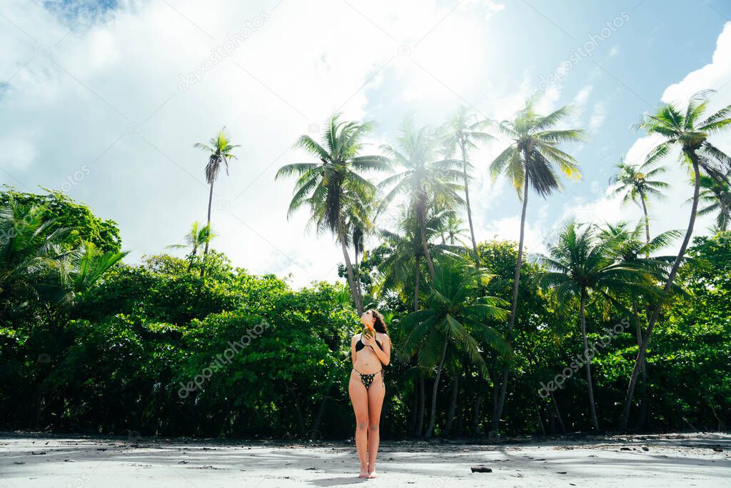 woman with a coconut on the beach of Manuel Antonio with the jungle