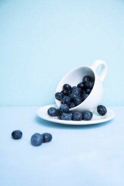 Vertical photo with blueberries fell on the table from a mug
